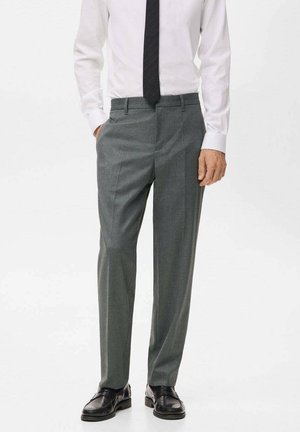 Pantalones grises de una tela de textura fina, con un diseño de pierna recta y pliegues sutiles, combinados con zapatos de cuero negros.