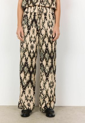 Pantaloni a gamba larga in crema, verde e un motivo astratto marrone. Tessuto leggero con vita elasticizzata. Indossati con scarpe nere lucide.
