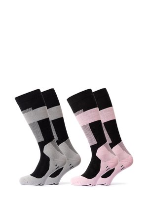 Hände, die schwarze und pinke kniehohe Sportsocken an Füßen vor weißem Hintergrund anpassen.