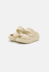 Zoccoli di un leggero color beige con due ampie cinghie e fori di ventilazione. Presentano una suola spessa e imbottita con interno texturizzato per un maggiore comfort.