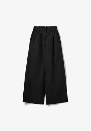 Pantalon large noir avec taille élastique, poches latérales et fermeture par bouton, posé à plat sur un fond blanc.