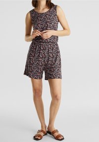 Combinaison à motifs floraux avec un bodice ajusté et une taille élastique, fabriquée en tissu léger. Les couleurs comprennent du bleu foncé, du rose et des accents blancs.