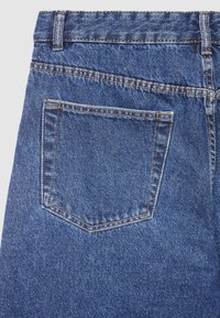 Jean en denim bleu avec une poche arrière unique ornée d'un motif en losange, fini avec une couture jaune contrastante. Tissu texturé.