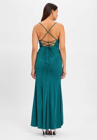 Teal satin evening dress with a fitted bodice, spaghetti straps, and crisscross lacing at the back, flowing to a flared skirt.