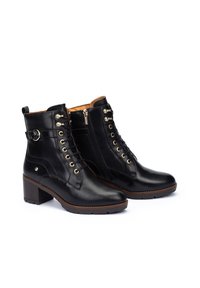 Botas de tobillo de cuero negro con punta redonda, herrajes dorados, cordones en la parte delantera y cremallera lateral. Presenta un tacón bajo tipo bloque y una suela texturizada.