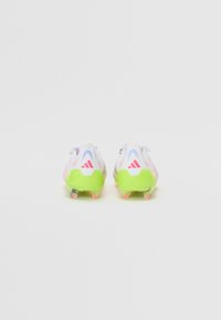 White soccer cleats with vibrant pink and green accents, featuring a textured upper, a curved design, and molded studs for traction.