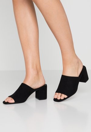Sorte ruskind åbne tå-mules med en bred overside, blød tekstur og en chunky firkantet hæl, der giver stabilitet og komfort.