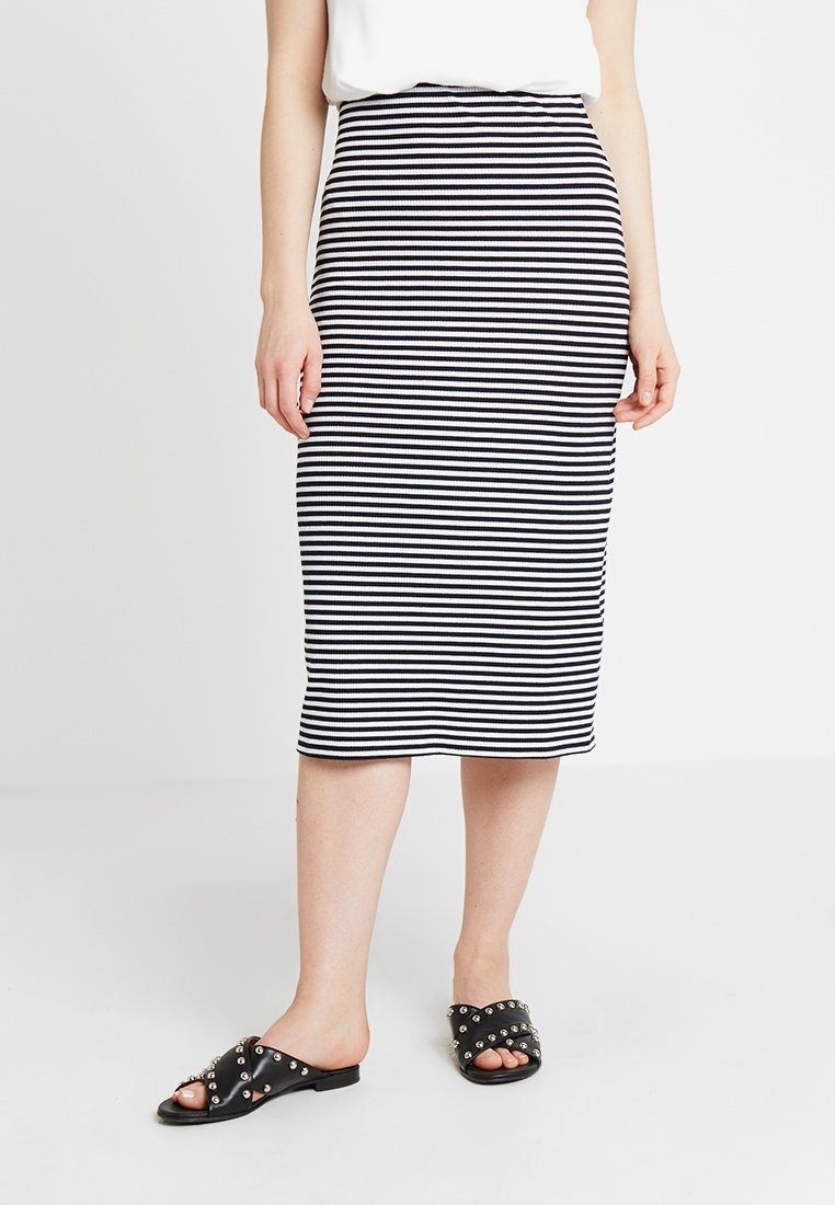 Páskovaná midi sukně v černobílé barvě z žebrované tkaniny s přiléhavým střihem. V kombinaci s černými skluznými sandály se hroty.