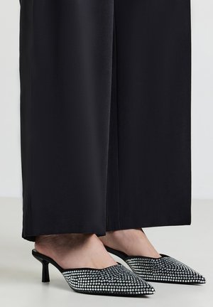 Mule a punta in satin nero con un brillante motivo di strass, caratterizzate da un sottile tacco a spillo e design aperto sul retro.
