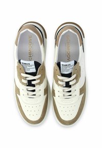 Baskets blanches et beiges en cuir et daim, avec une boîte à orteils perforée, un design à lacets et un accent noir sur le côté.