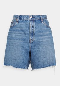 Shorts de mezclilla azul con cintura alta, botón y cremallera en la parte delantera, cinco bolsillos y bordes deshilachados.