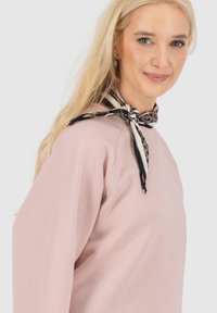 Lichtroze sweatshirt met lange mouwen, ronde halslijn en een zwart-wit gestreepte nek sjaal die aan de voorkant is gestrikt. Dikke textuur.