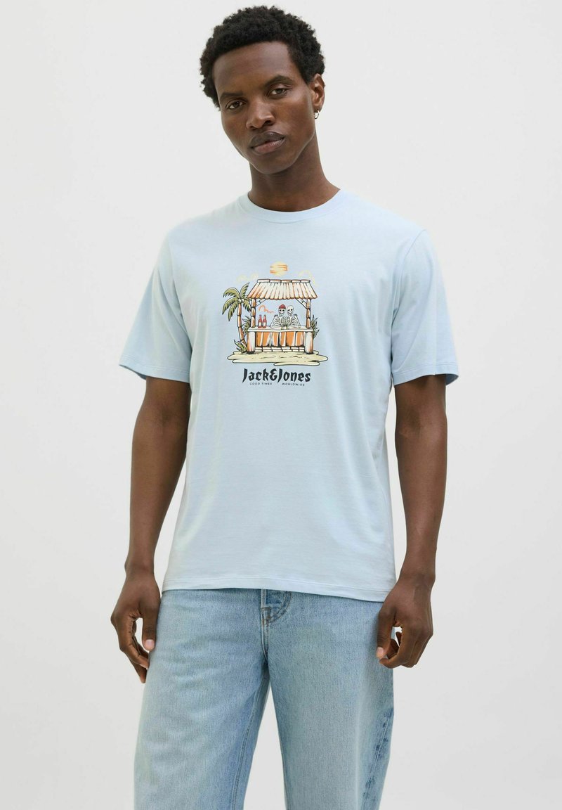 Lichtblauw katoenen t-shirt met korte mouwen, met een grafisch ontwerp aan de voorkant van een strandbar met palmbomen en de tekst "Jack & Jones" onderaan.