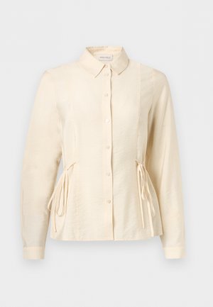 Blouse à manches longues couleur crème avec boutons sur le devant, col classique et liens latéraux ajustables pour une taille cintrée.