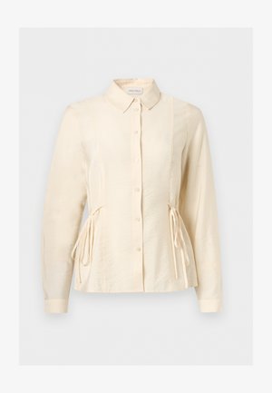 Blouse à manches longues couleur crème avec boutons sur le devant, col classique et liens latéraux ajustables pour une taille cintrée.