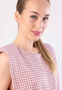Rosa-weißer karierter ärmelloser Oberteil mit rundem Halsausschnitt, aus strukturiertem Stoff und in lässiger Passform. Das Model hat lange, glatte Haare.