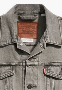 Giubbotto in denim grigio con colletto a punta, chiusura con bottoni e etichetta in pelle Levi's. Tessuto testurizzato con cuciture ben visibili e tasche.