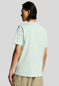 Camiseta de algodón verde menta claro con mangas cortas, cuello redondo y corte relajado, que presenta una textura suave y un diseño minimalista.