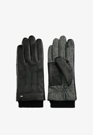 Gants en cuir noir avec tissu en chevrons, dotés d'un poignet en tricot côtelé et d'un logo subtil. Paume texturée avec une finition douce.