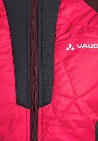 Pink padded jacket featuring a zip closure, black accent panels, and a quilted texture. Logo printed in white on the right side.