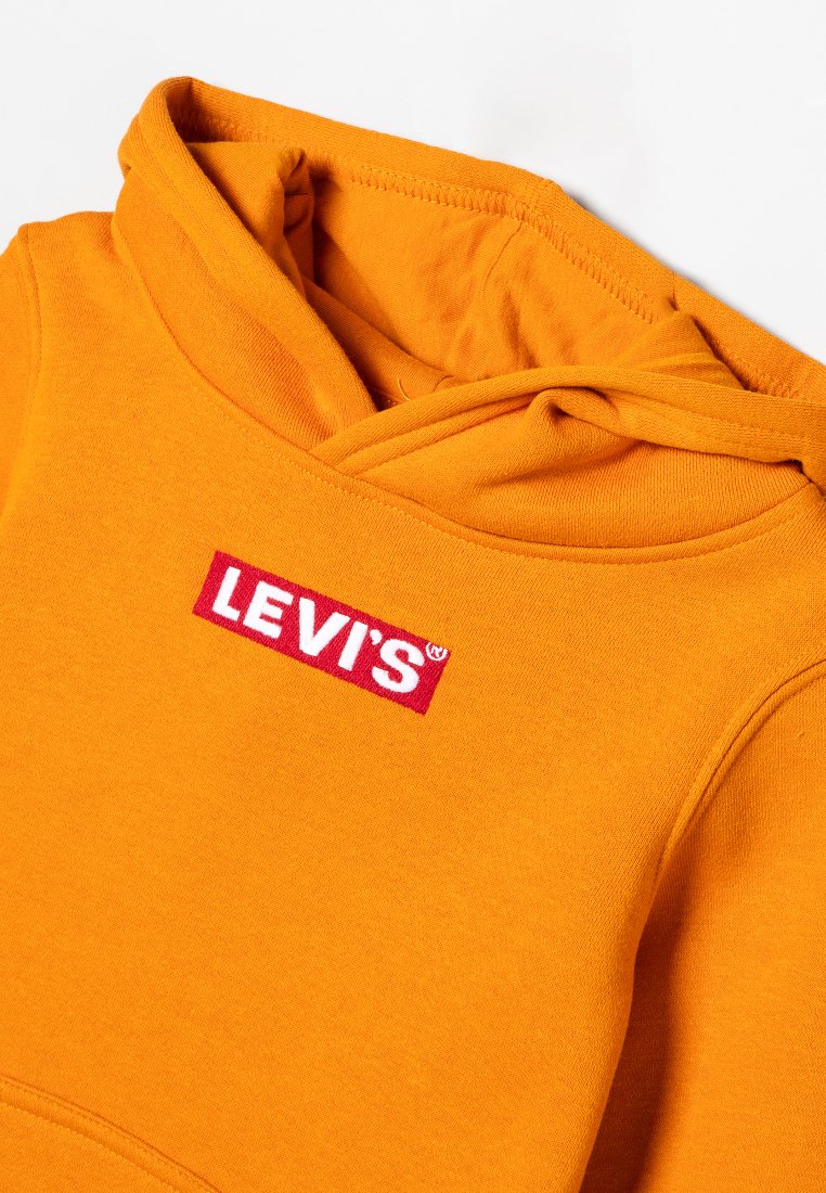 Haut à capuche orange en coton avec une texture en polaire ; présente un patch logo rouge Levi's à l'avant et une capuche réglable par cordon.