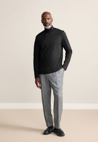 Sort, langærmet rullekravetrøje kombineret med lysegrå, skræddersyede bukser og sorte pæne sko. Glat stof med en figursyet pasform.