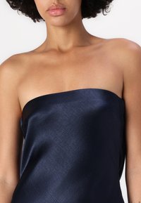 Απαλή μπλε σατέν τοπ χωρίς straps με λεία υφή και ελαφριά γυαλάδα. Διαθέτει ίσια λαιμόκοψη και μινιμαλιστικό σχέδιο.