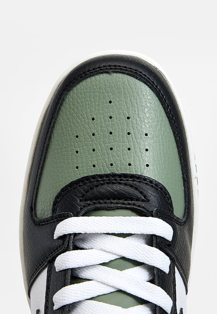 Sneaker in pelle nera e verde con lacci bianchi, caratterizzato da una tomaia verde testurizzata, dettagli perforati e una punta nera a contrasto.