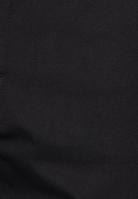 Černá džínová látka s hladkou texturou a diagonálním vazebním vzorem. Jemný šev podél okraje, bez viditelných vzorů nebo kovových prvků.