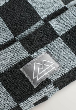 Strickmütze mit einem schwarz-grauen Karomuster und einem kleinen grauen Stoffetikett, das ein stilisiertes Logo zeigt. Weiche Textur.