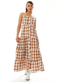 Maxi dress in brown and white gingham pattern, featuring adjustable straps, button front, and tiered ruffle hem; lightweight fabric.