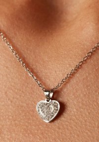 Zilveren harthangerketting met heldere rhinestones, met een gladde afwerking en een delicate ketting, rustend tegen de huid.