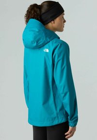 Giacca impermeabile turchese con cappuccio, presenta il logo The North Face sulla parte superiore della schiena, maniche lunghe e un design flessibile per l'abbigliamento outdoor.