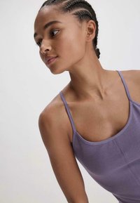 Lila tanktop met dunne bandjes, met een aansluitend ontwerp en een soepele textuur. Zichtbare naaddetails benadrukken de structuur van het kledingstuk.