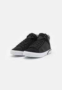 Las zapatillas altas negras presentan un upper de tela suave, acentos texturizados, cordones redondos y una suela de goma blanca.