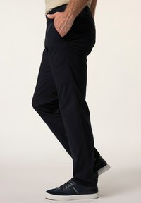 Marina byxor med slim fit, tillverkade av strukturväv. Har sidofickor och elastisk midja, kombinerat med mörka sneakers.