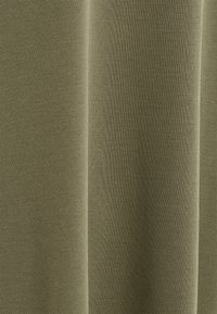 Tissu vert olive avec une texture douce et lisse. Tricot léger avec un motif subtil, présentant des plis verticaux et un effet drapé.