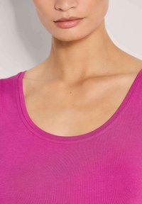Enges rosa Tanktop mit Rundhalsausschnitt und glatter Textur; es verfügt über schmale Nähte am Ausschnitt und an den Schultern.