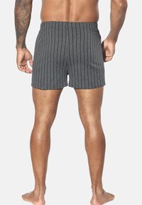 Grau gestreifte Swim-Shorts mit elastischem Bund, knielang und weicher Textur, von hinten betrachtet.