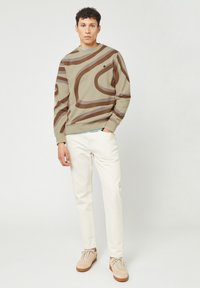 Felpa a maniche lunghe con motivo marrone e beige, collo a giro. Abbinata a pantaloni chiari e sneakers beige. Design a vestibilità dritta.