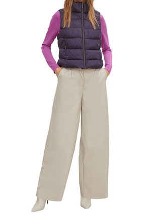 Kamizelka puchowa w ciemnopurpurowym kolorze, z zamkiem z przodu, zestawiona z różową bluzką z długim rękawem i szerokimi beżowymi spodniami, wykończona kremowymi botkami za kostkę.