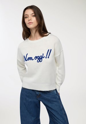 Maglione bianco lavorato a maglia con testo ricamato blu "Non oggi!!" al centro. Vestibilità comoda con scollatura rotonda e orlo a coste. Pantaloni in denim.