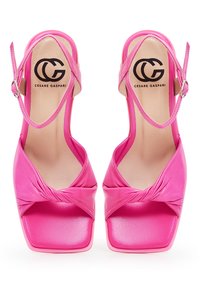 Sandalias de tacón rosa con acabado de cuero suave, punta cuadrada y detalle de tira retorcida. Correa ajustable en el tobillo con hebilla en tono plateado.