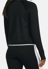 Svart träningströja med långa ärmar, som har en vit kant, ribbade muddar och en slät, stretchig tygdesign.