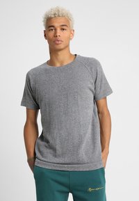 Tricou gri cu mânecă scurtă, cu guler rotund, are un material texturat și mâneci raglan. Purtați-l cu pantaloni teal și accente minime.
