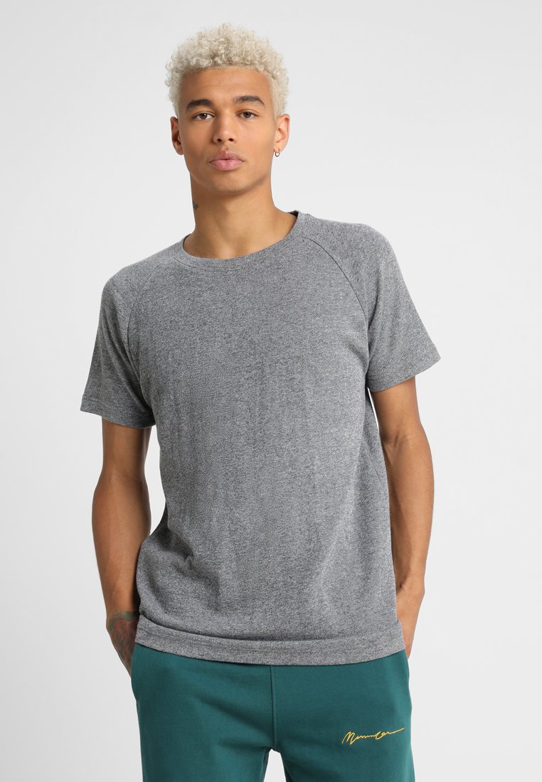 Tricou gri cu mânecă scurtă, cu guler rotund, are un material texturat și mâneci raglan. Purtați-l cu pantaloni teal și accente minime.