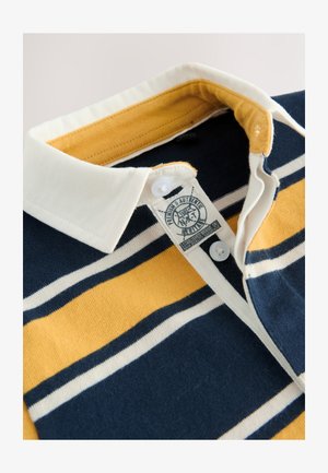 Bomuldspolo med horisontale striber i marineblå, gul og hvid. Hvid krave med knaplukning, synligt mærkat nær halsudskæringen.