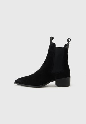 Black suede ankle boot with elastic side panels and pull tabs. Features a low block heel and pointed toe design for a sleek silhouette.