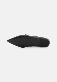 Zapato negro de punta con parte superior de cuero liso, suela de goma plana y diseño minimalista. Presenta una silueta elegante y sin hardware visible.