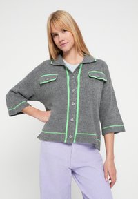 Hall halli kardigan roheliste detailide ja lühikeste varrukatega. Omab kahte klapiga taskut ja nööbid ees. Sile tekstuur.